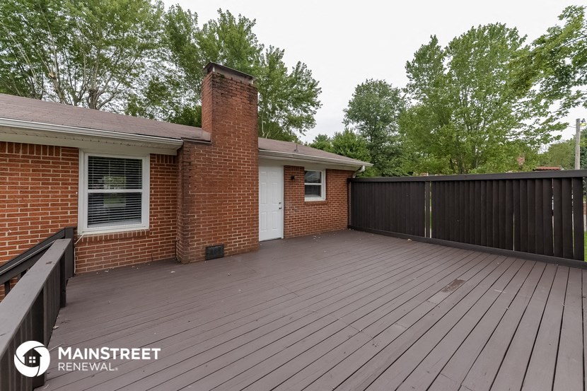 a large deck in front of a brick house with a black fence