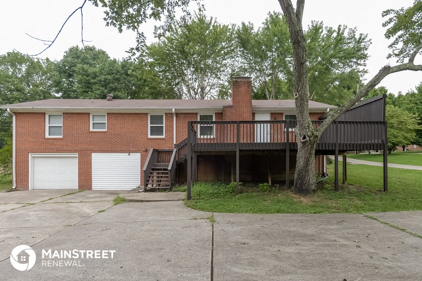 the front of a brick house with a deck and a tree