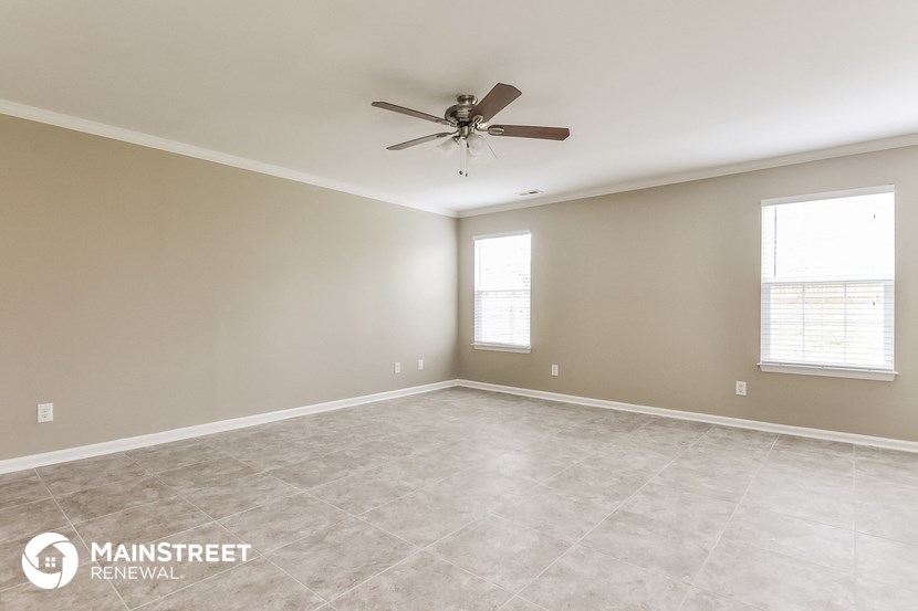 the spacious living room with ceiling fan and tile flooring