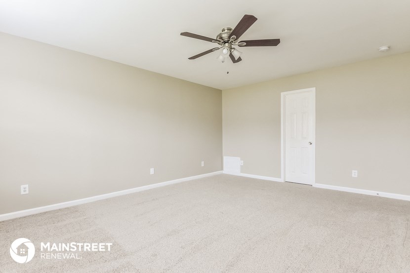 the spacious living room with carpet and ceiling fan