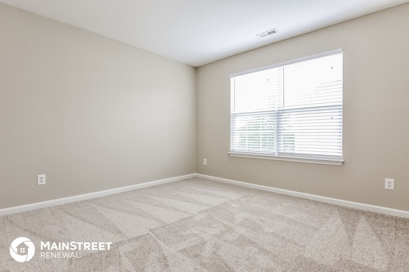 the spacious living room with a large window and carpeted flooring