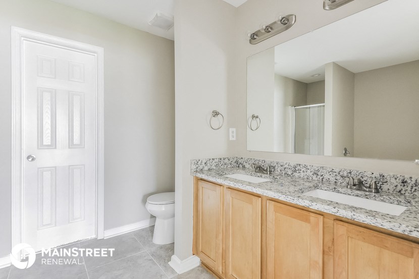 a bathroom with two sinks and a toilet and a large mirror