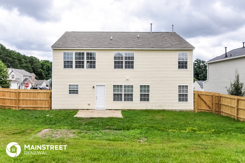 a backyard garage with a white house and a wooden fence