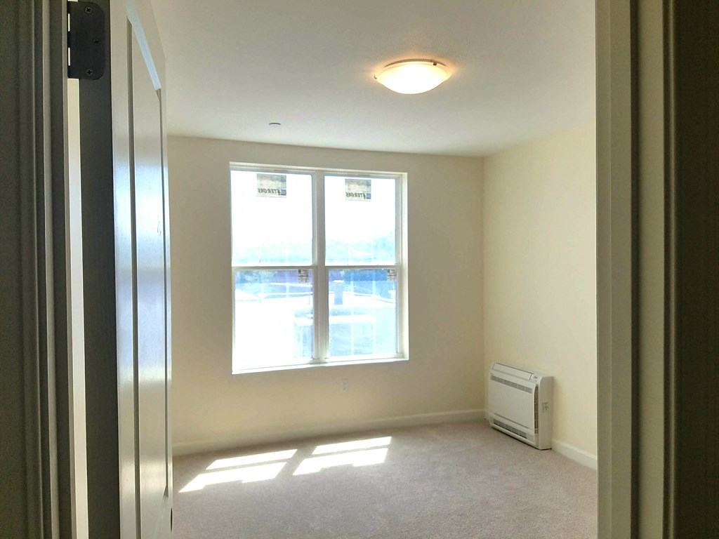 an empty room with a window and a radiator