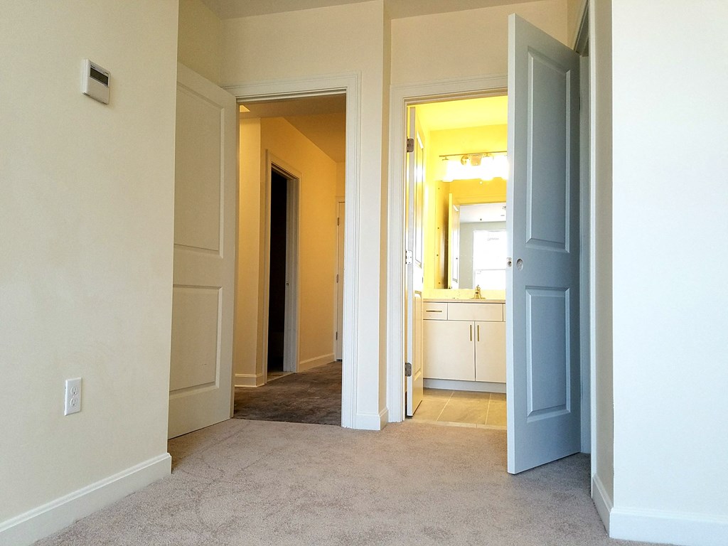 an empty living room with a hallway to a bedroom and a bathroom