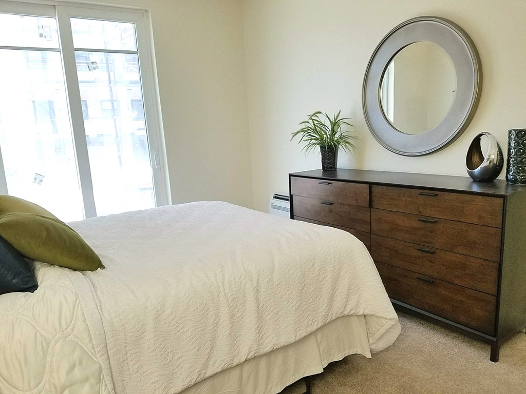 a bedroom with a bed and a dresser with a mirror