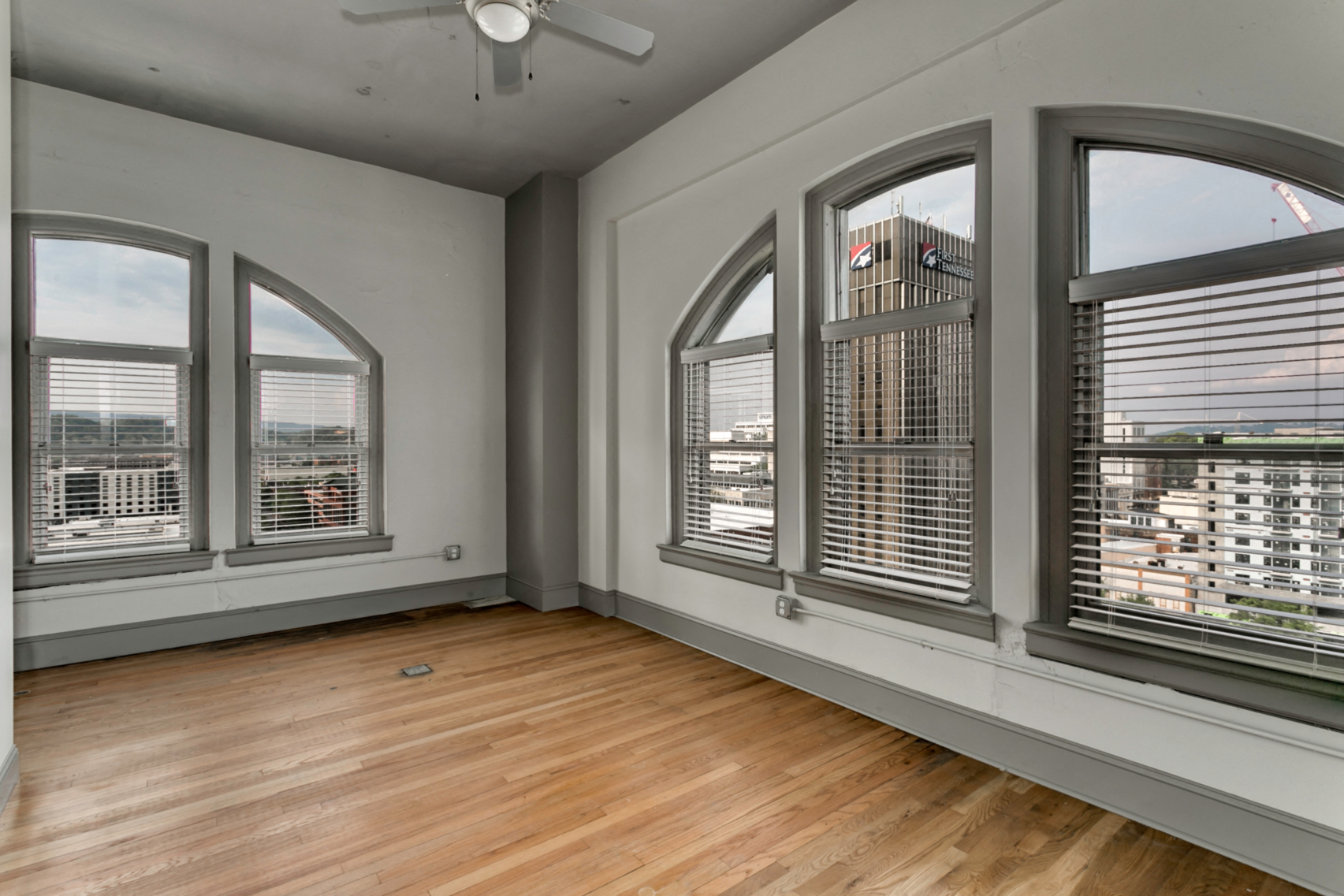 the living room of an apartment with large windows and wood floors