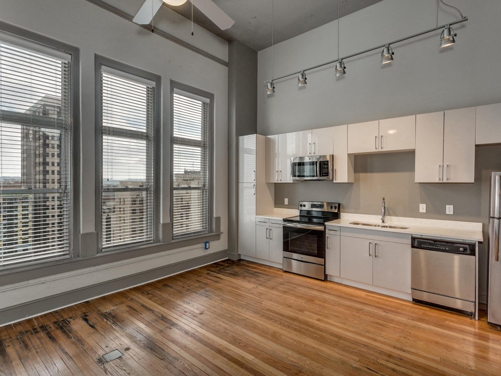 an empty kitchen with a large window and a wood floor