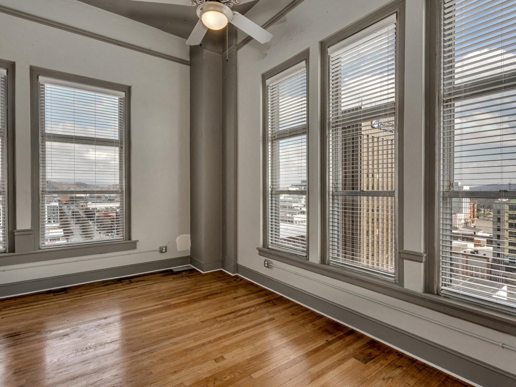 a living room with windows and wood floors and a ceiling fan