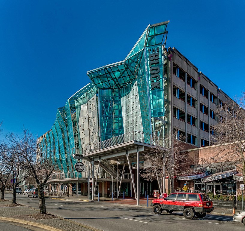 a red car parked in front of a building with a large green structure