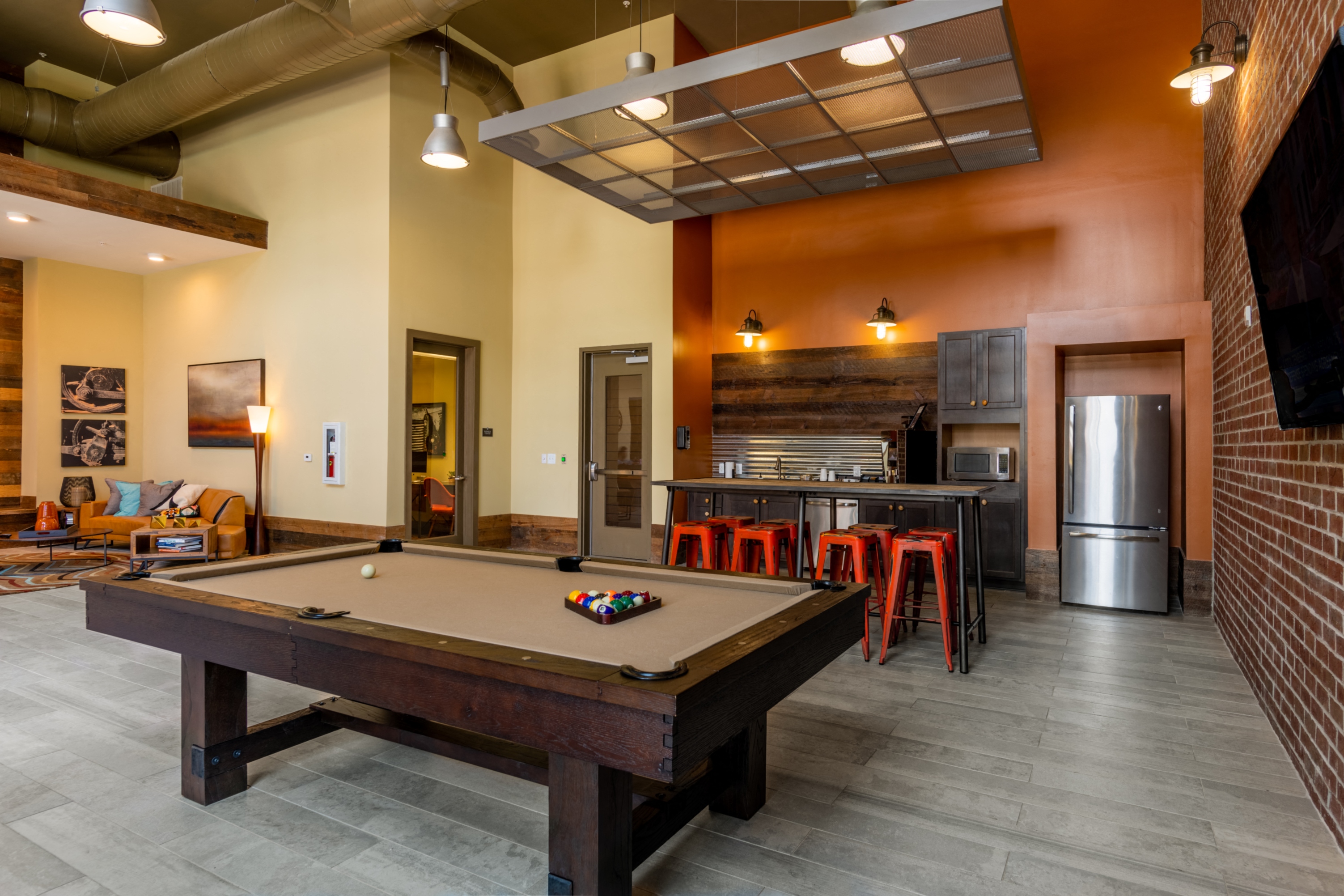 a pool table in a clubhouse with a bar and a kitchen