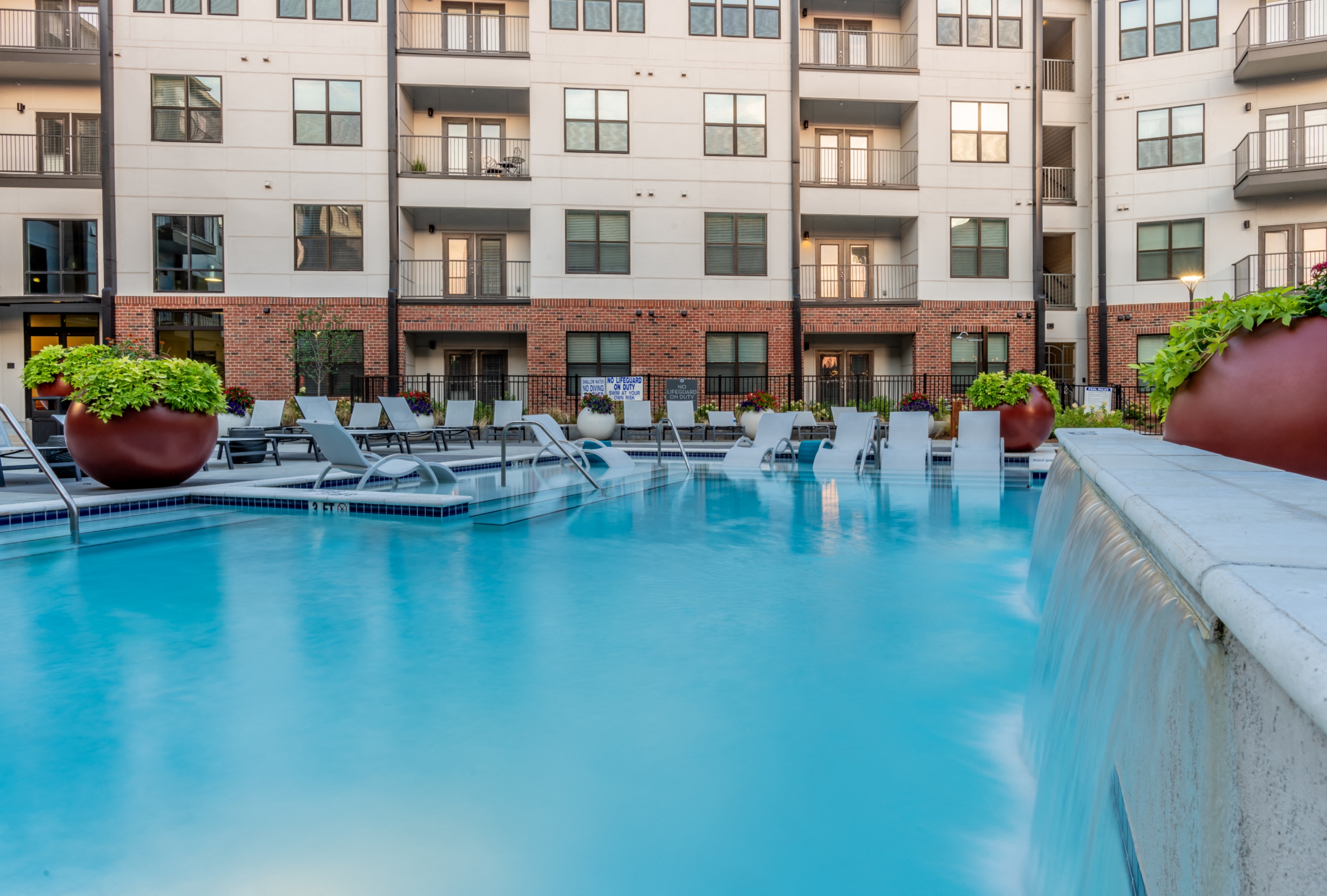 a swimming pool with lounge chairs in front of an apartment building