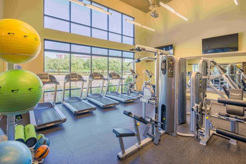 a gym with cardio equipment and windows