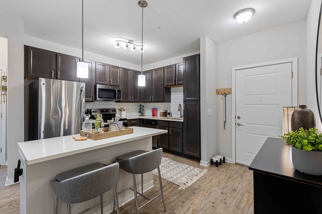 a kitchen with stainless steel appliances and a counter with chairs