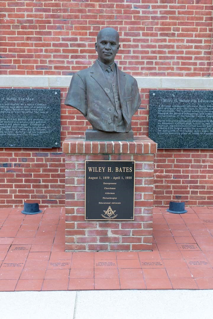 a statue of a man sitting on top of a brick wall