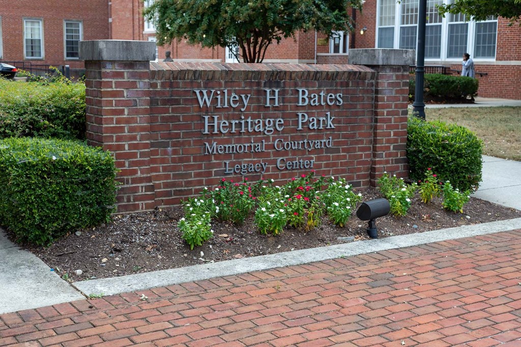 a brick sign with flowers in front of a brick wall
