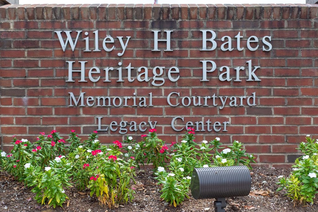 a brick wall with a sign on it and some flowers