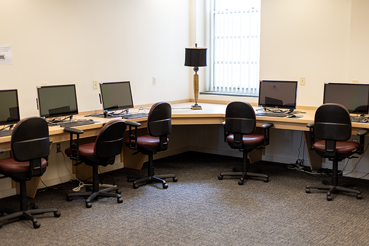 a group of desks with computers and chairs in a room