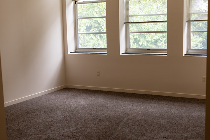 an empty room with two windows and a carpeted floor