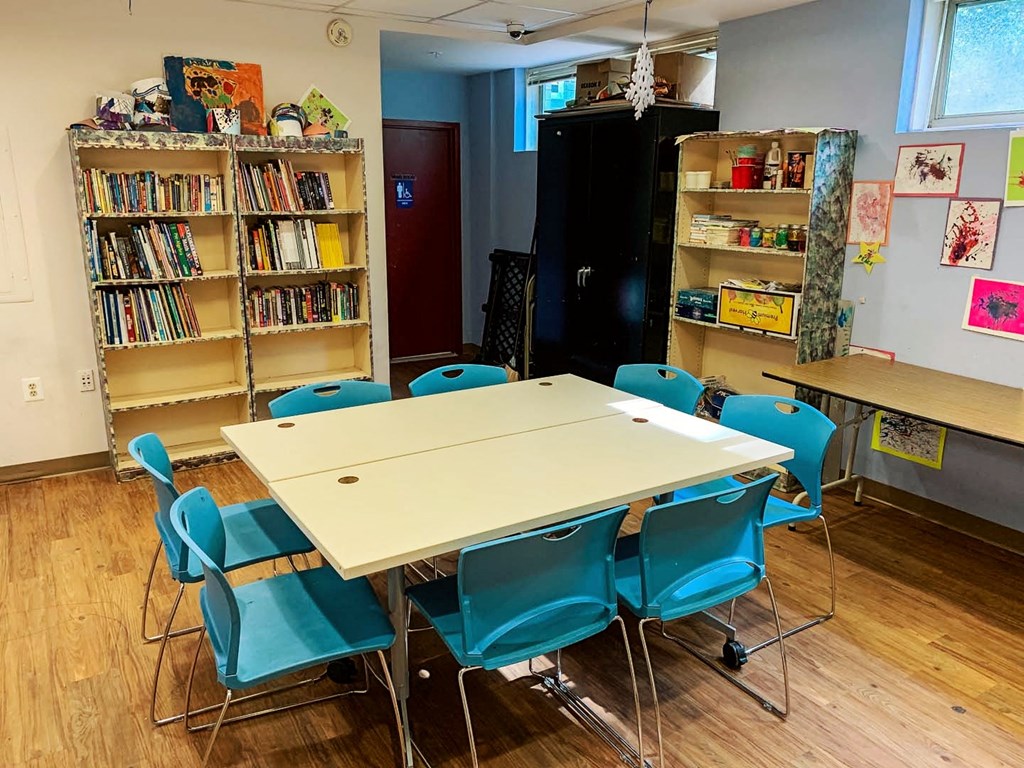 a classroom with a table and chairs and bookshelves