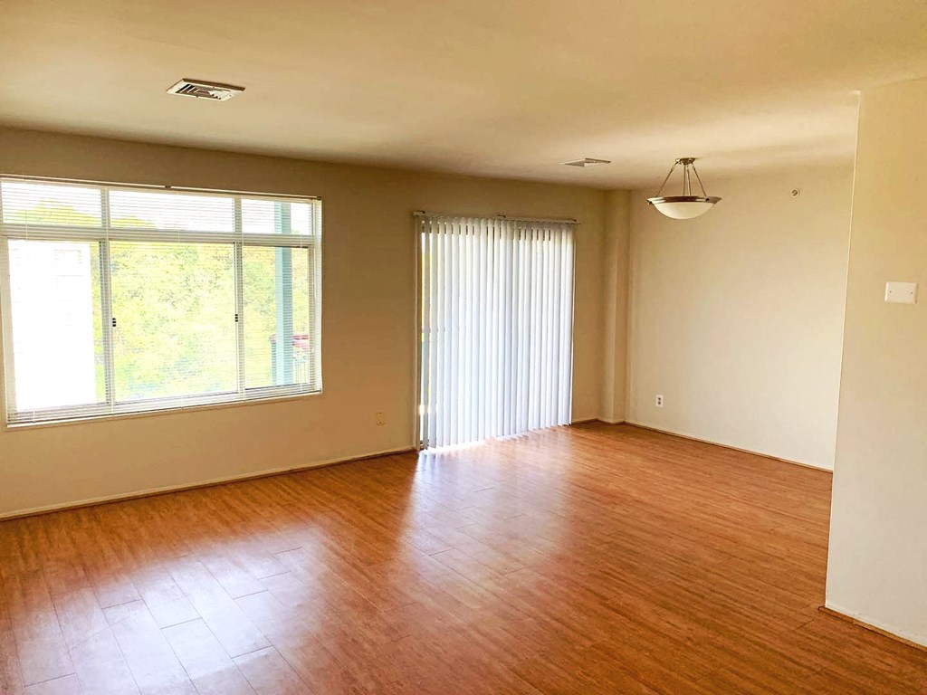 an empty living room with wood floors and a window