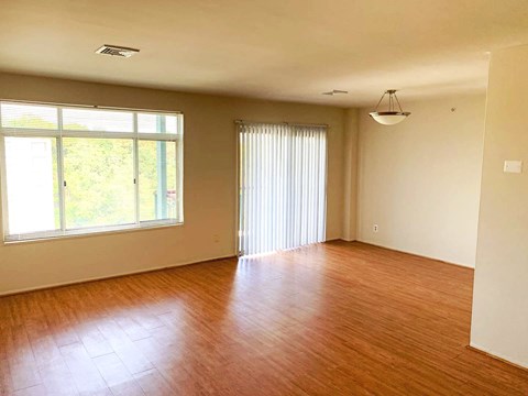 an empty living room with wood floors and a window