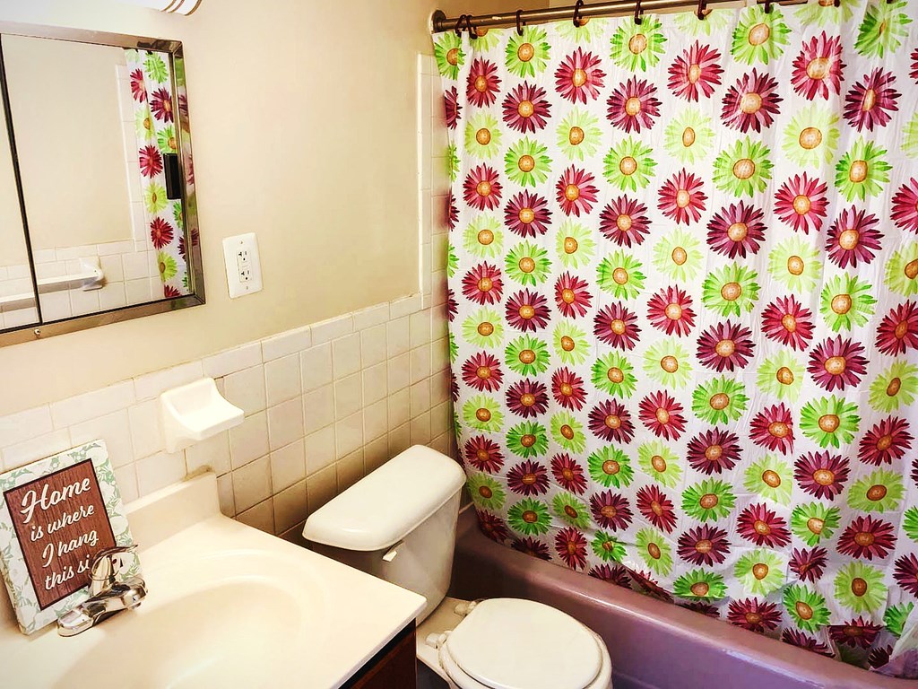 a bathroom with a shower curtain and a sink and a toilet