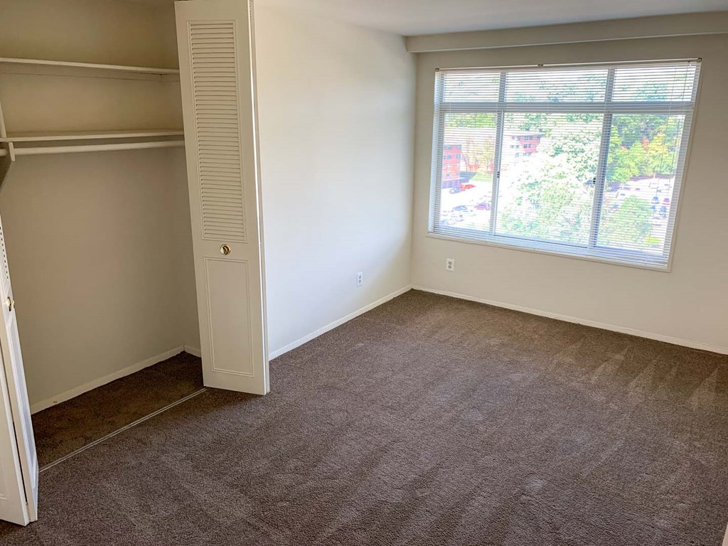 an empty room with a window and a closet