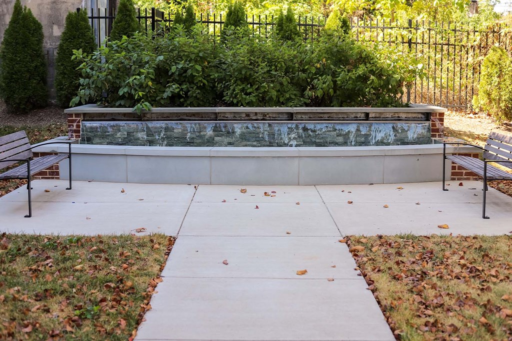 a concrete patio with two benches in front of a fountain