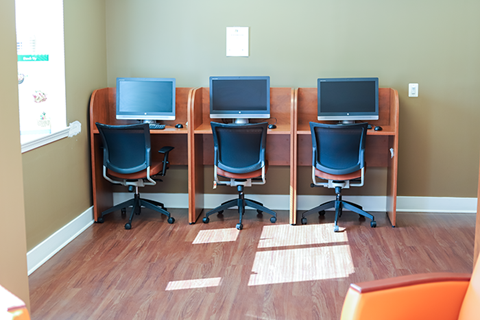 a row of computer desks with three monitors on top of them