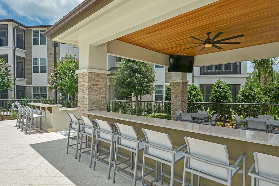 a patio with a bar and chairs in front of a building