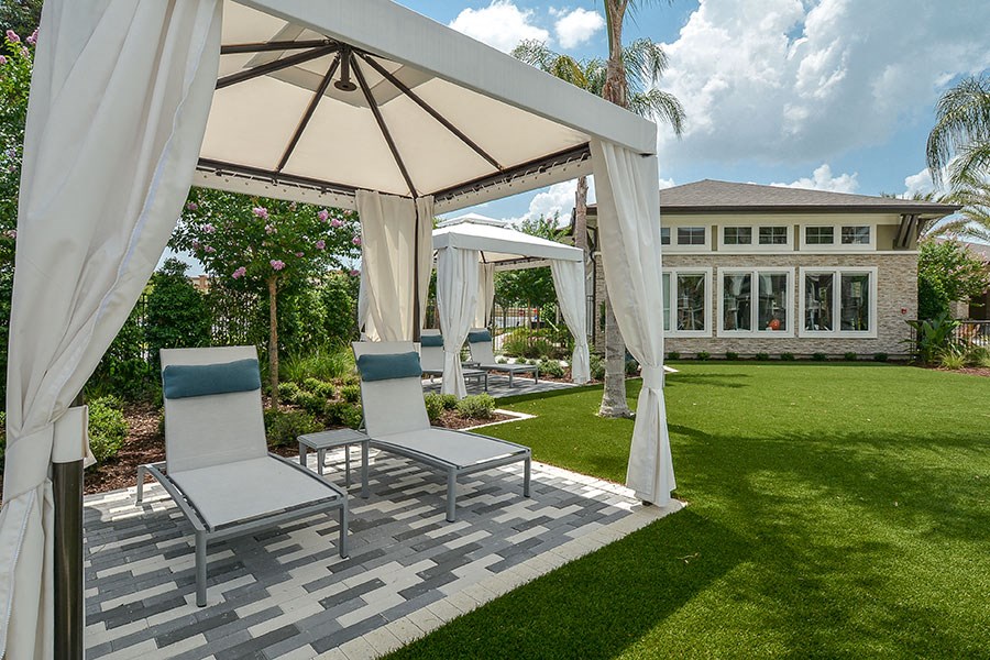 a patio with chairs and umbrellas in front of a house