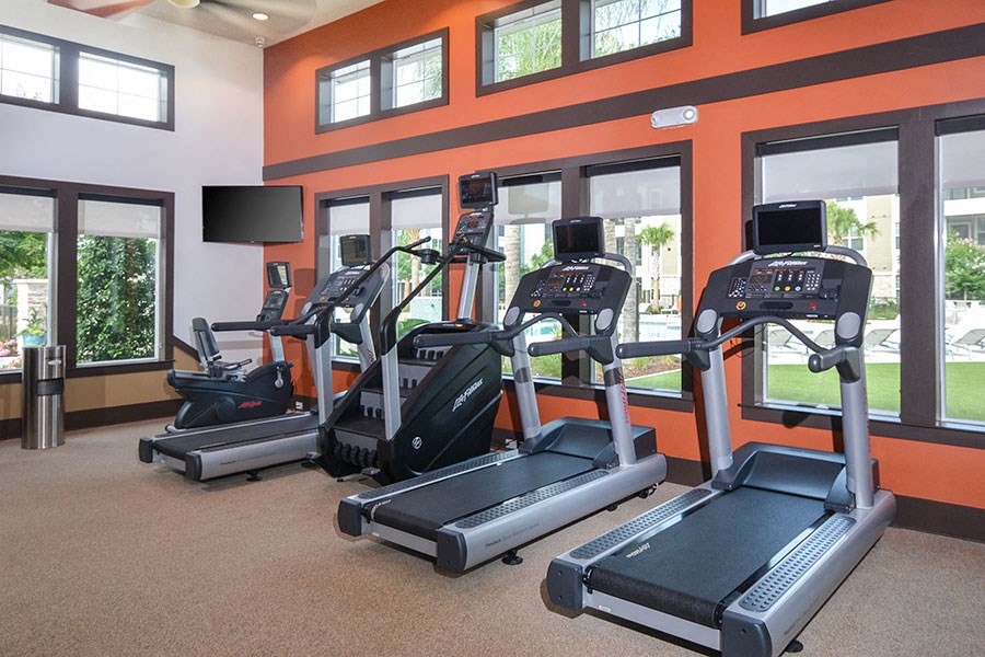 a gym with cardio equipment and windows in a building