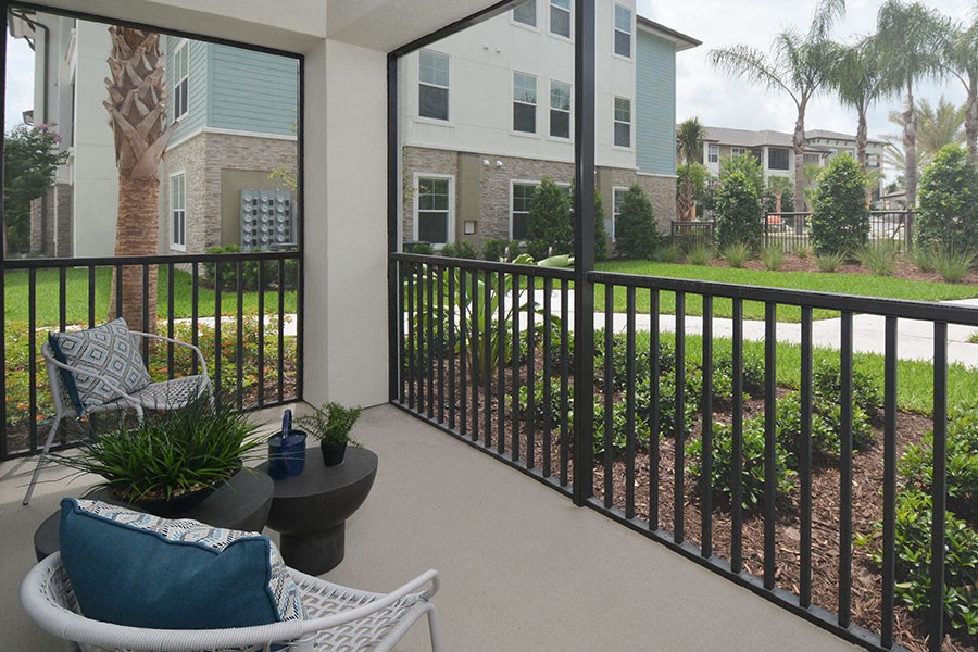 a balcony with chairs and a view of a yard and a building
