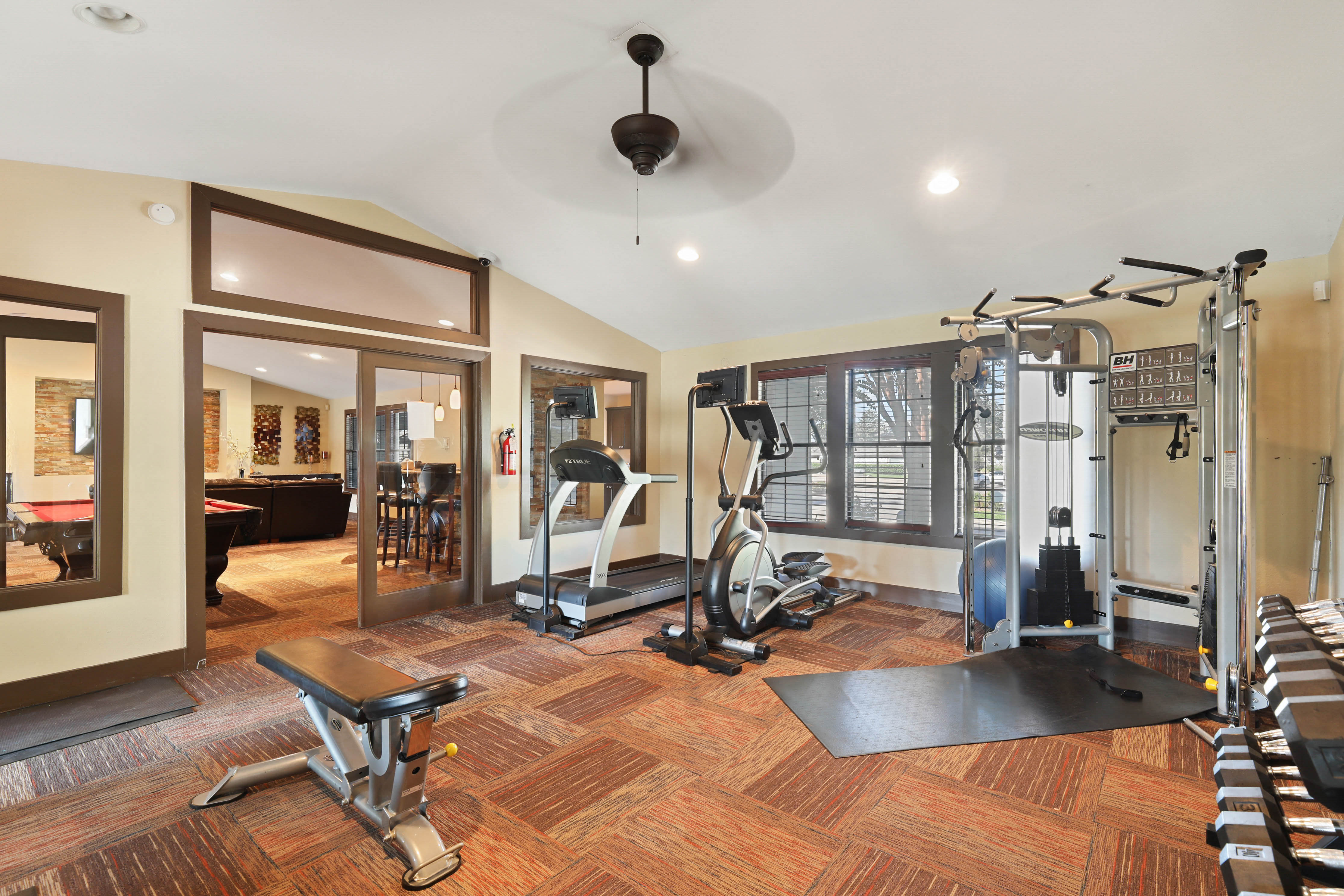 a gym with treadmills and weights in a home gym with a large window