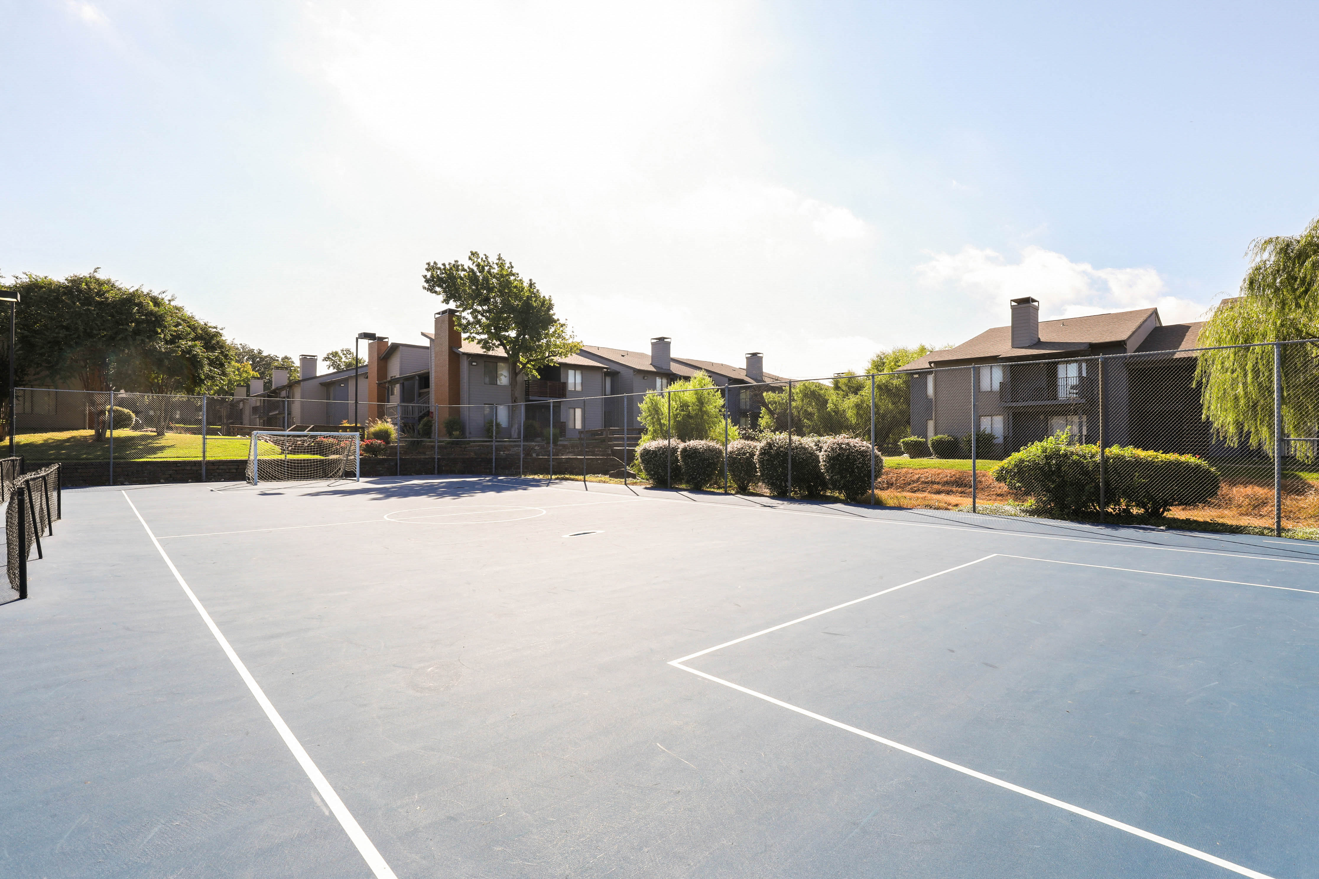 a tennis court with apartments in the background