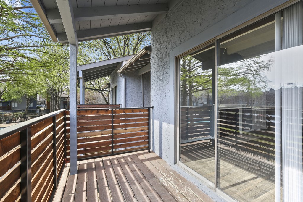 a balcony with a wooden railing and a glass door