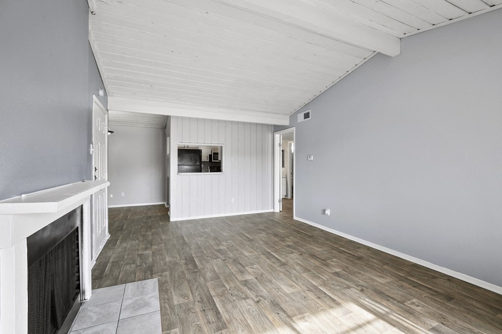 the living room and dining room of a house with wood flooring and a fireplace