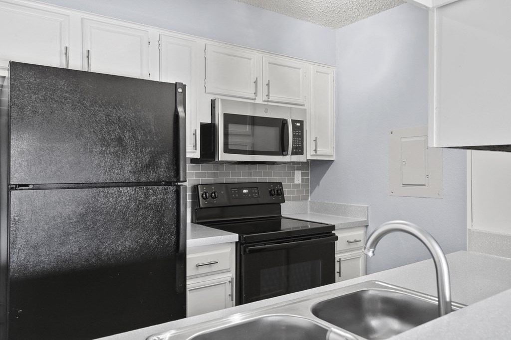 a kitchen with black appliances and white cabinets