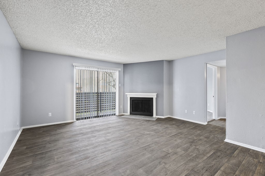 an empty living room with a fireplace and wood flooring