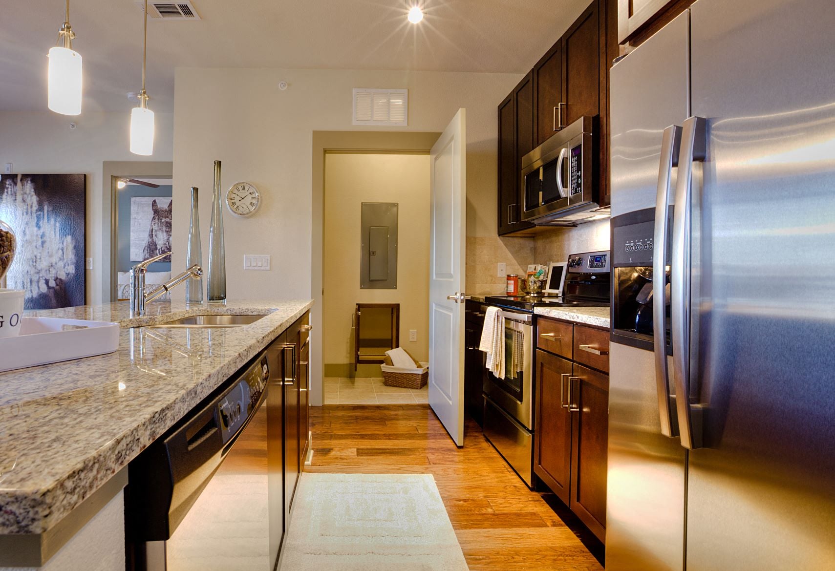 A modern kitchen with a refrigerator on the right and a sink in the middle.