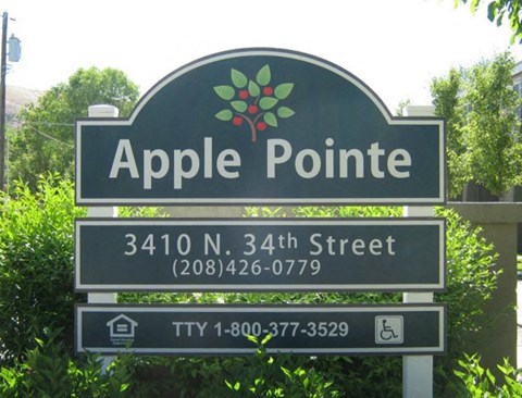 a sign for apple pointe in front of trees