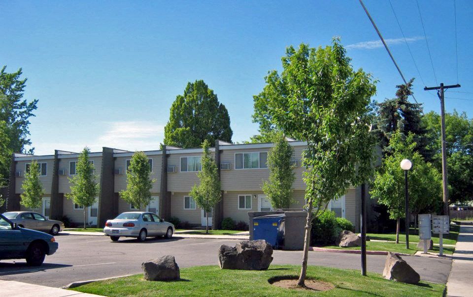 an apartment building on the corner of a street with cars