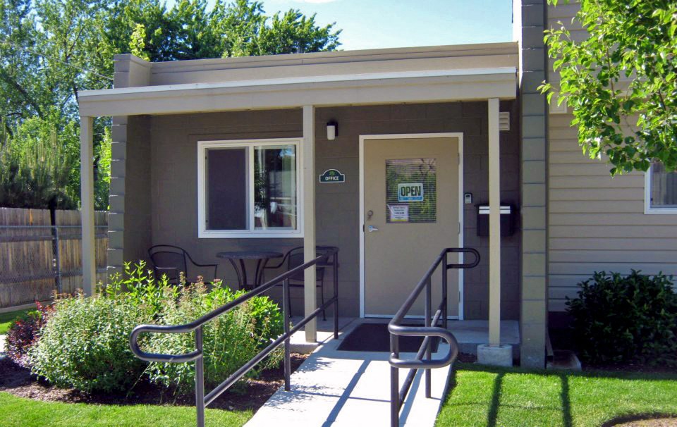 the front entrance of a small brown building with steps and a porch