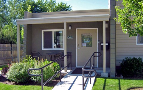 the front entrance of a small brown building with steps and a porch