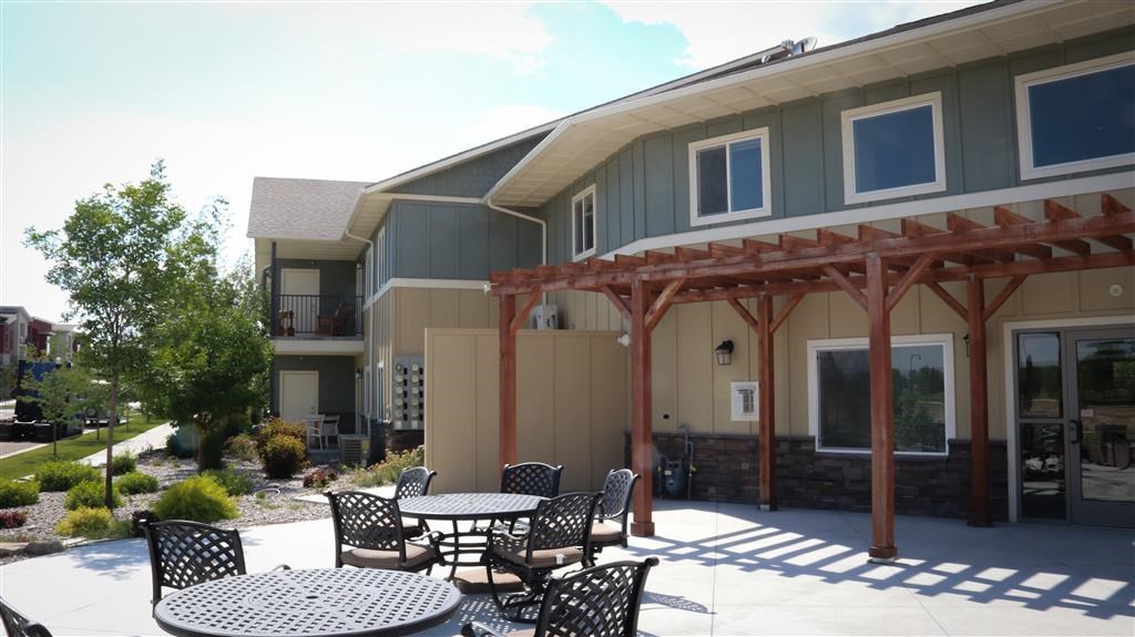 a patio with tables and chairs in front of a house