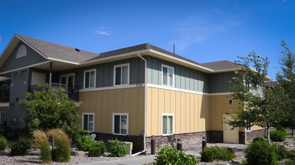 a yellow and green house with a stone wall