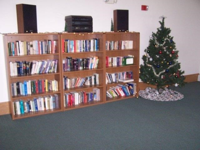 a library with a christmas tree next to a shelf of books