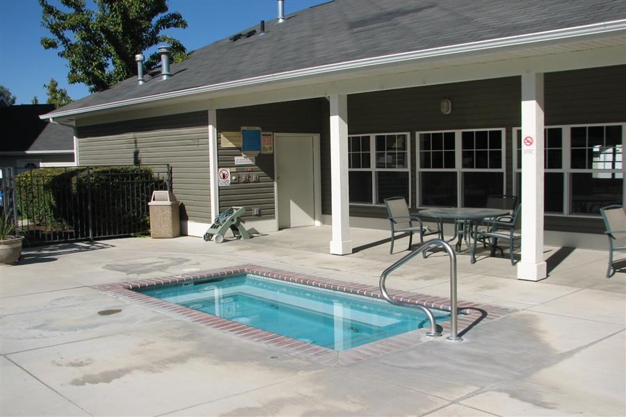 a swimming pool in front of a house with a patio