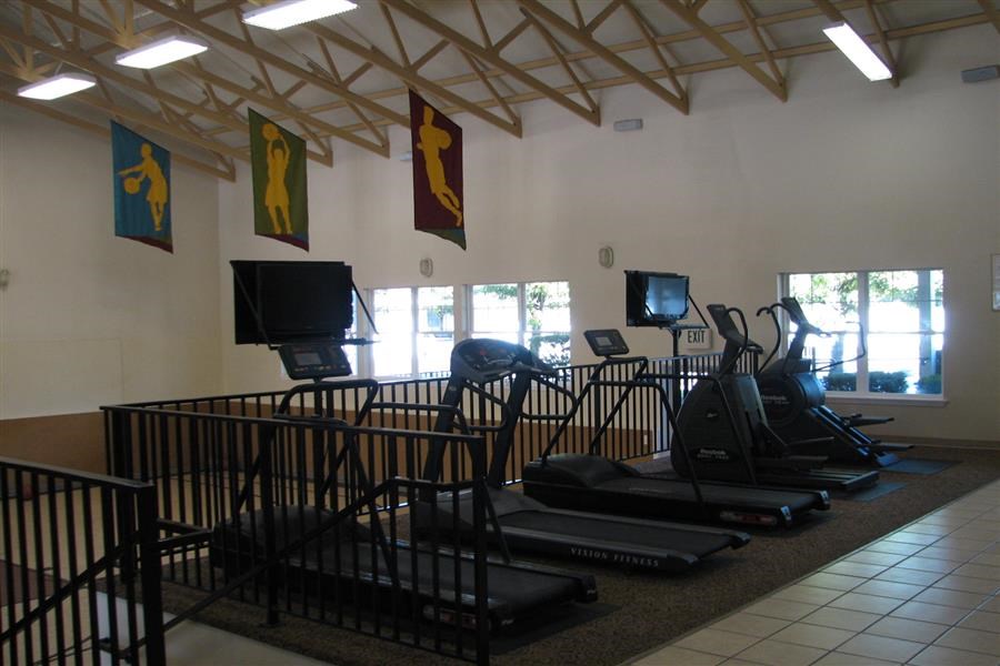 a gym with exercise equipment and monitors in a room